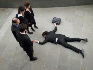 Business people looking down at man lying on pavement, elevated view